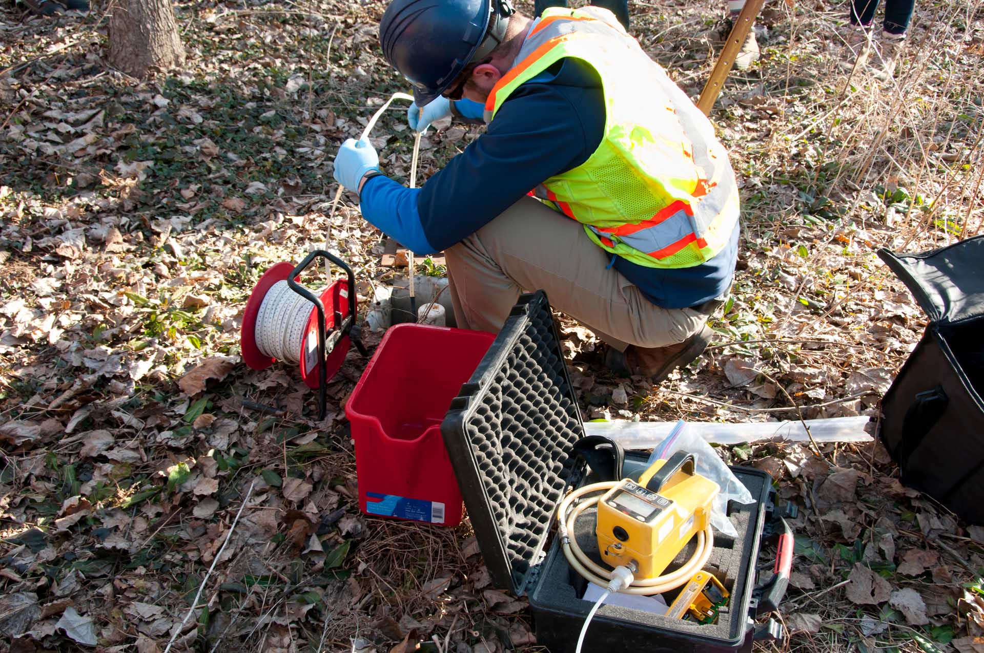 A person in safety gear is performing field testing with a variety of equipment.