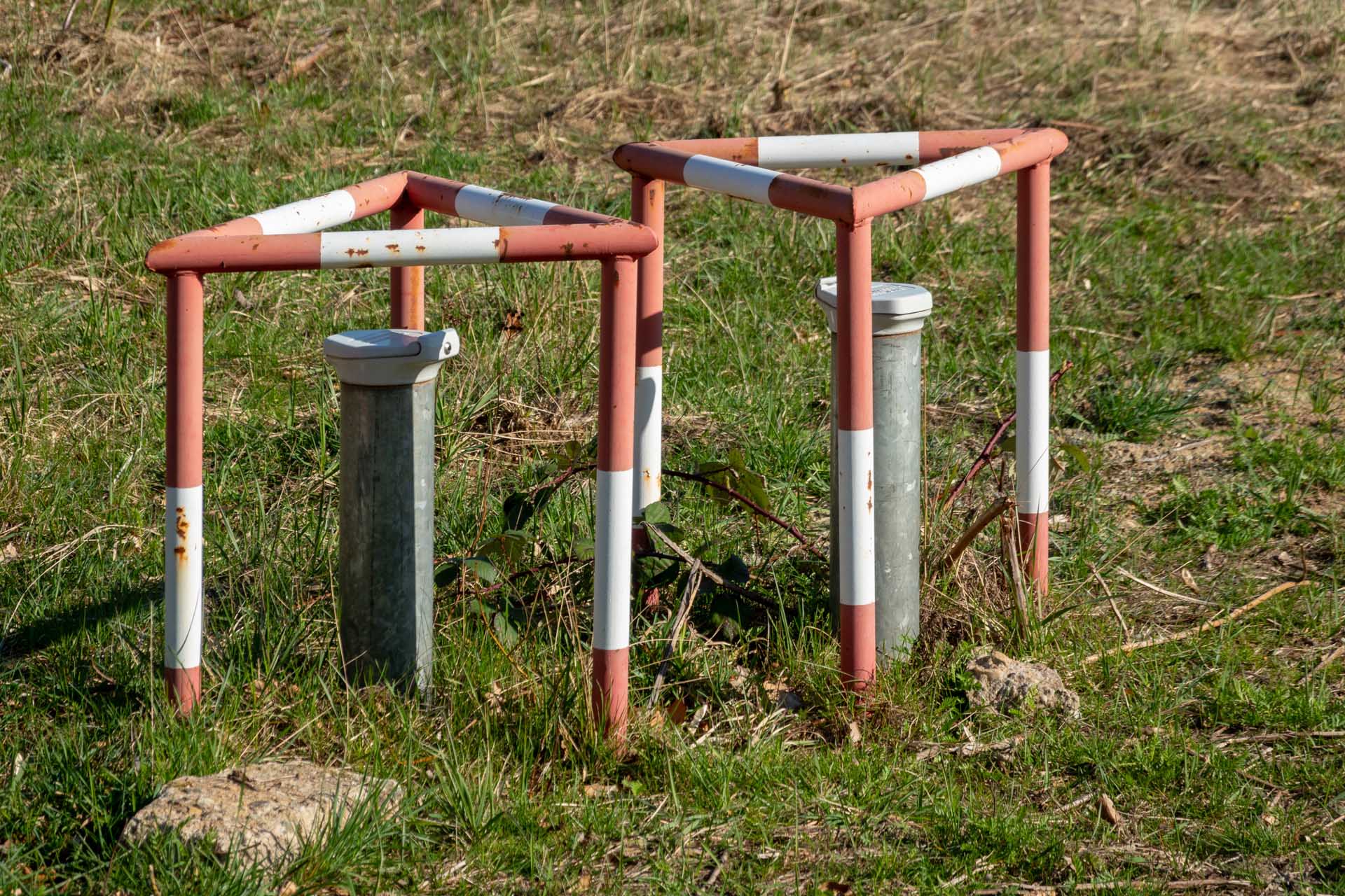 Two red and white painted posts, with a white plastic cap on top, are used to define a boundary.