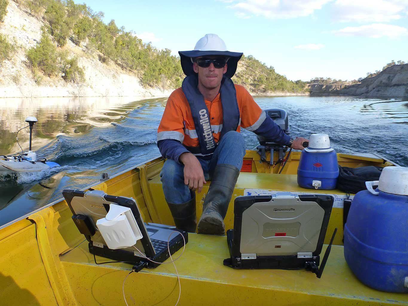 Hydrographics worker in boat equipped with measuring instruments on a river