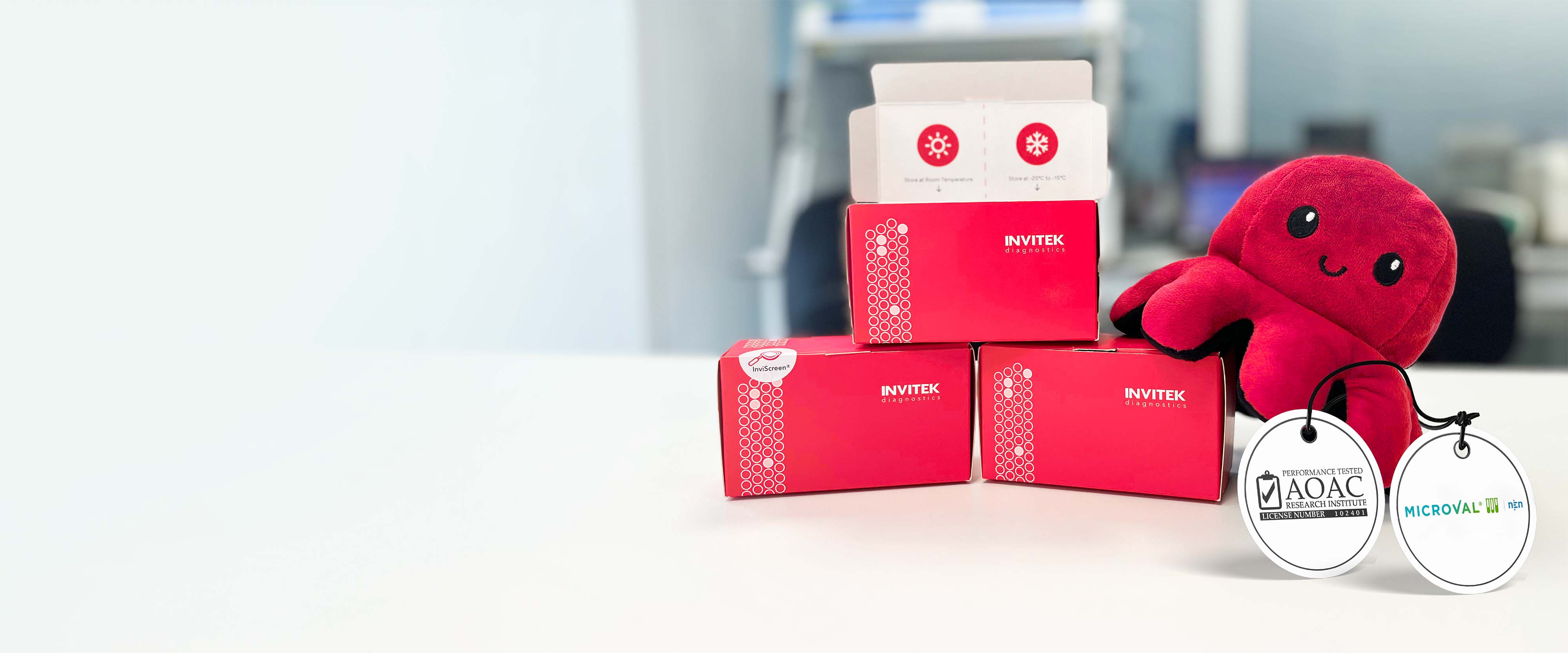 Three red boxes containing qPCR reagents for Salmonella ssp detection from Food Matrices. The boxes are labelled with MicroVal and AOAC certifications and equivalence methods. There is also a red octopus alongside the kits, this is the Brand Mascot
