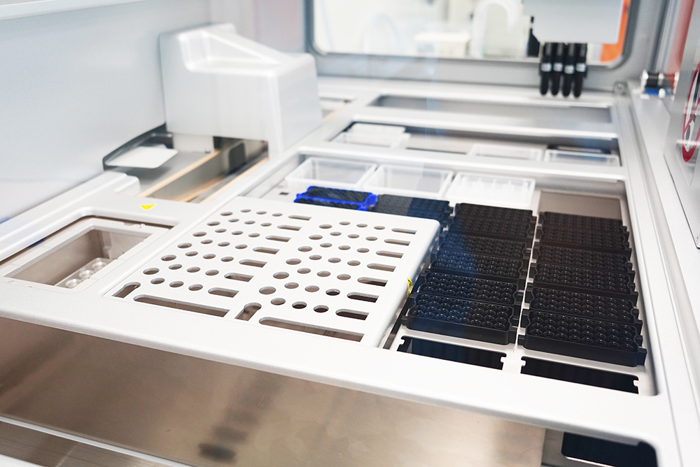 Automated liquid‑handling deck with racks and microplates inside a lab instrument.