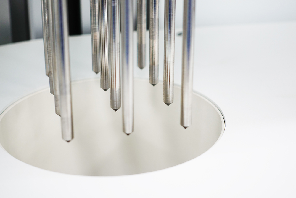 Close‑up of stainless‑steel pipette probes descending into an instrument bay