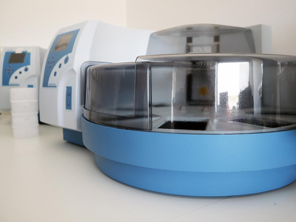 Benchtop blue centrifuge–style extractor with transparent lid in a laboratory.