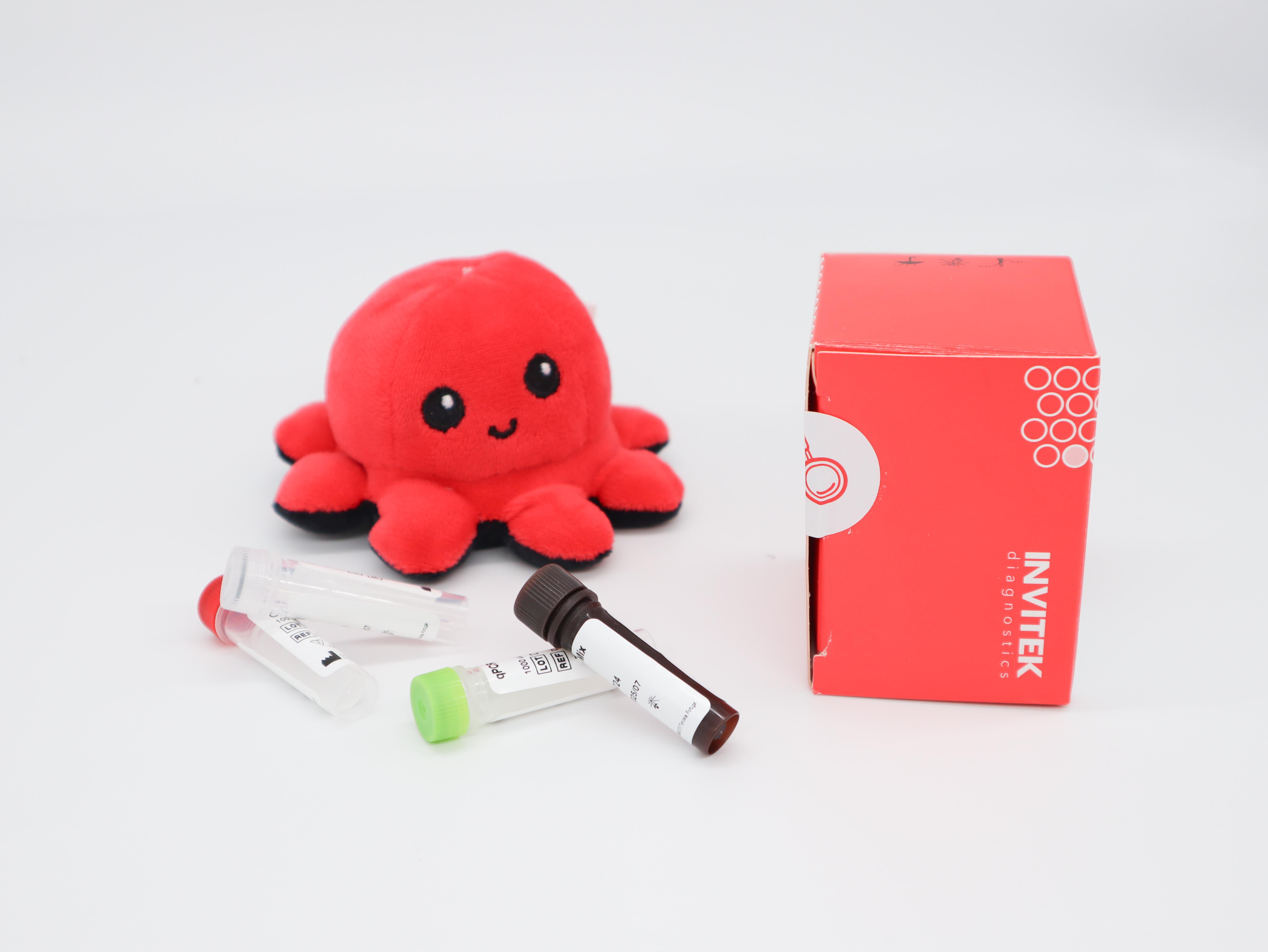 InviScreen SARS-CoV-2 4G kit: plush octopus beside red INVITEK box, with mixed reagent vials (clear, green, brown caps) lying in foreground.
