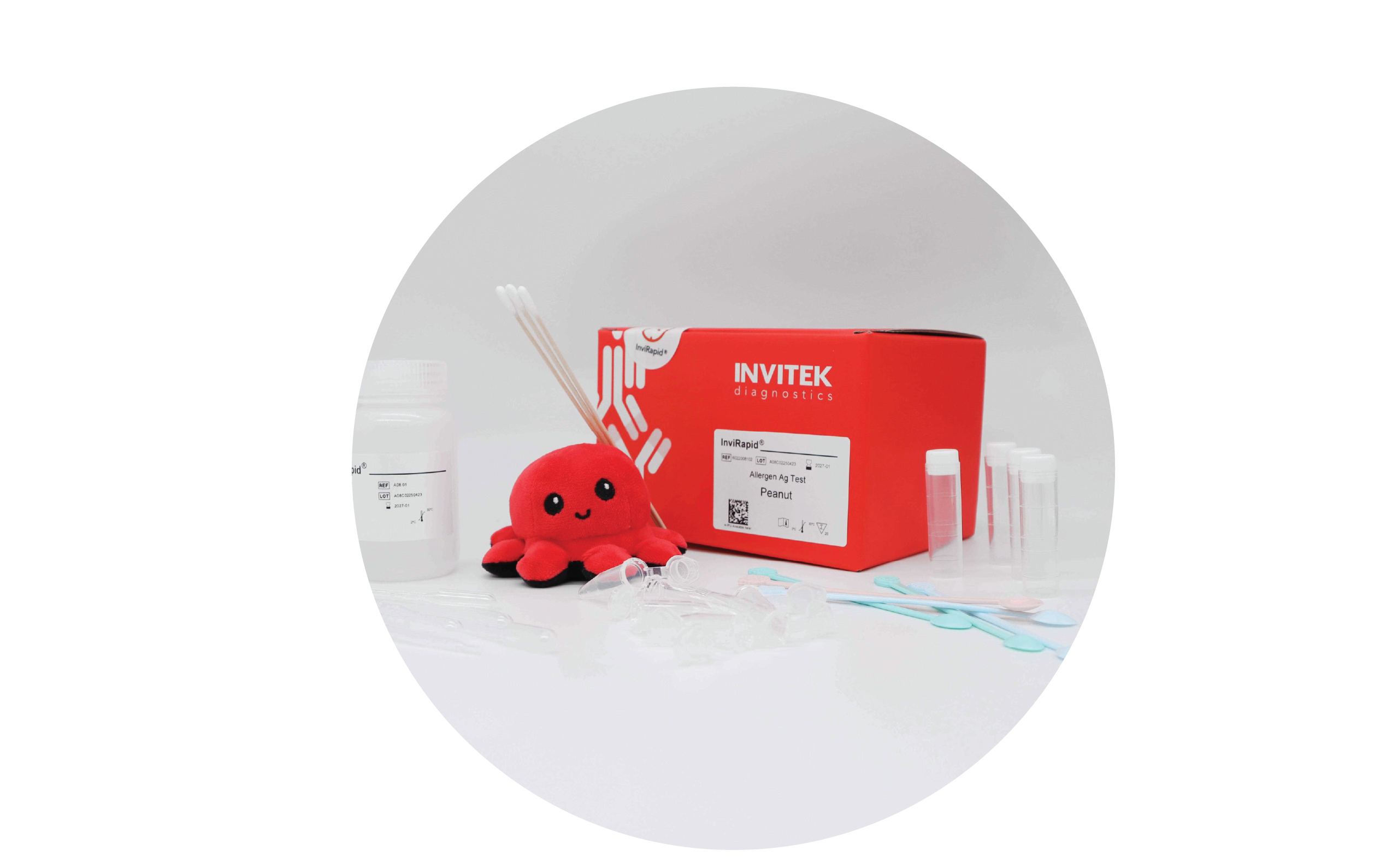 Red Invitek Diagnostics InviRapid Peanut Allergen Ag Test box behind sample tubes and swabs next to a buffer bottle with scoops, droppers and tubes laying scattered in front.