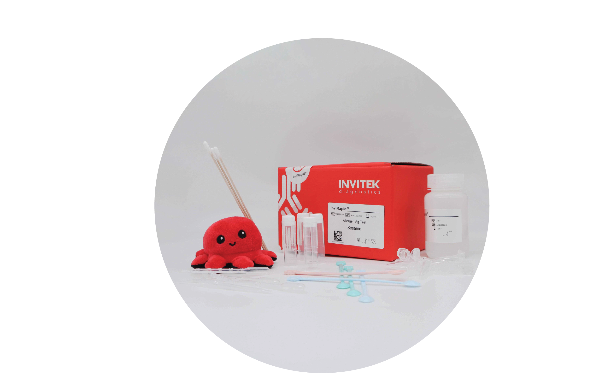Red Invitek Diagnostics InviRapid Sesame Allergen Ag Test box behind a buffer bottle and sample tubes next to swabs with scoops, droppers and tubes laying scattered in front.