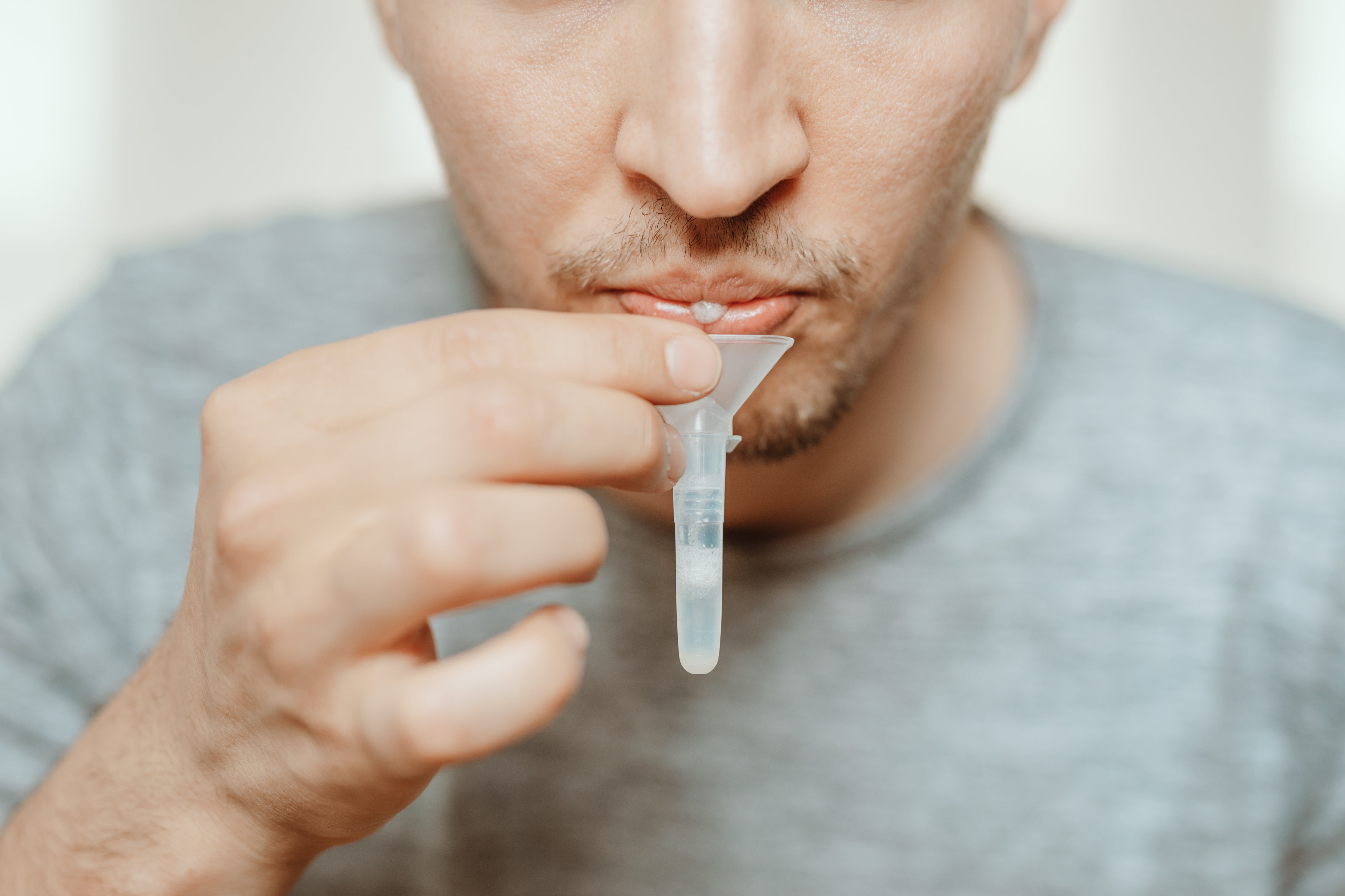 collecting saliva - spit with mouth through funnel in plastic tube to collect sample