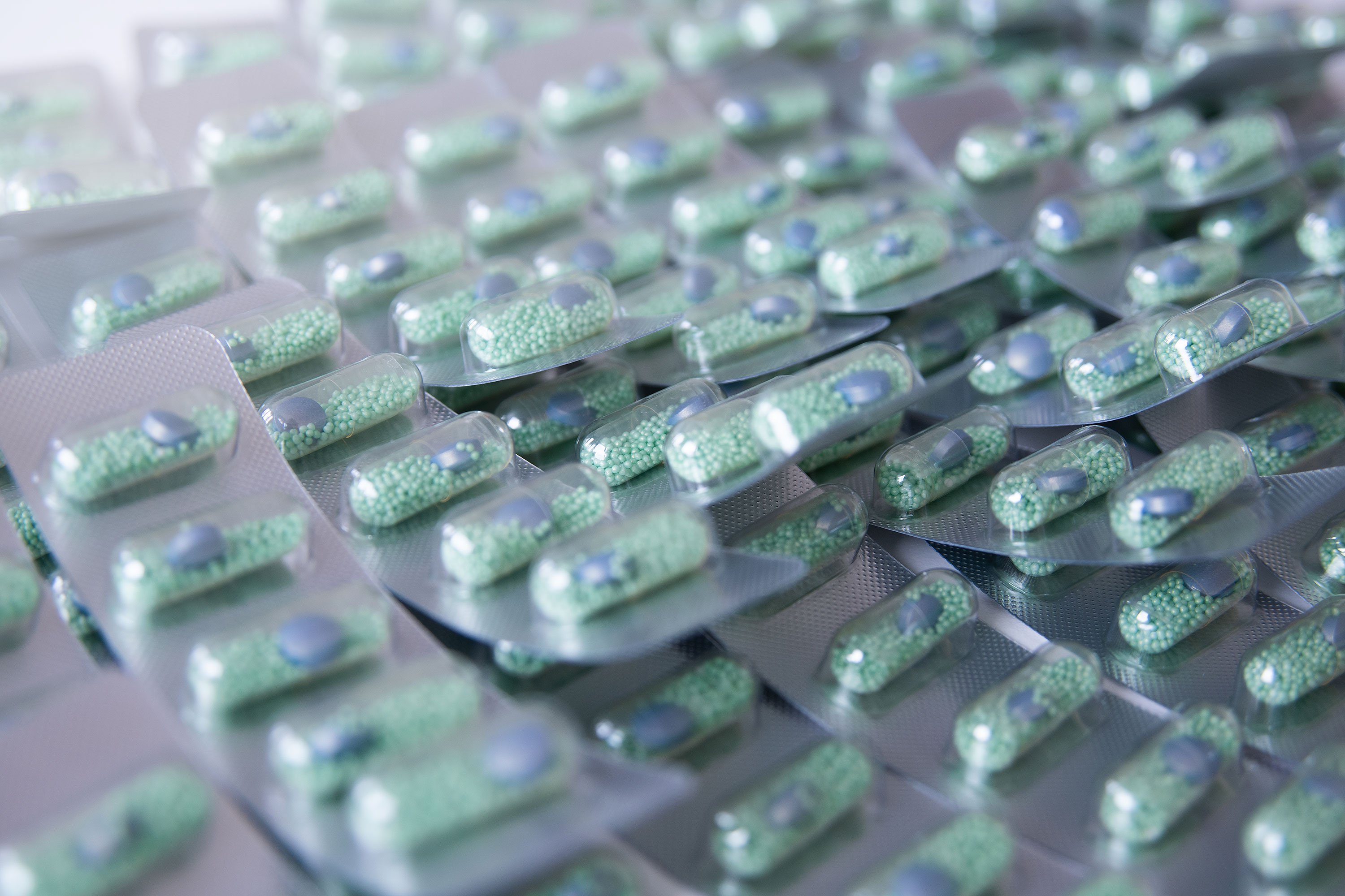 Transparent capsules containing blue tablet and green granules into metallic blisters