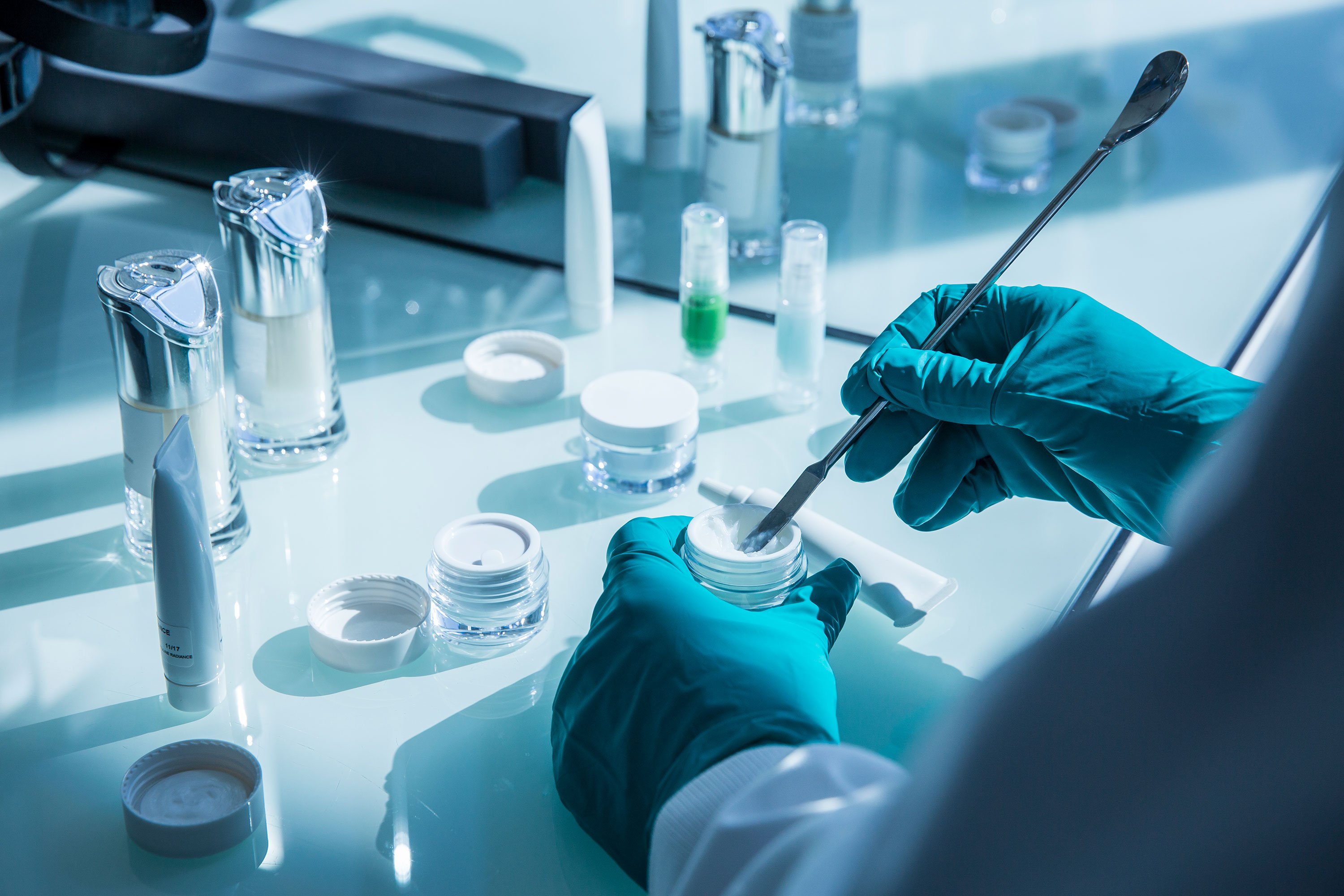 Two hands in gloves doing cream formulation 