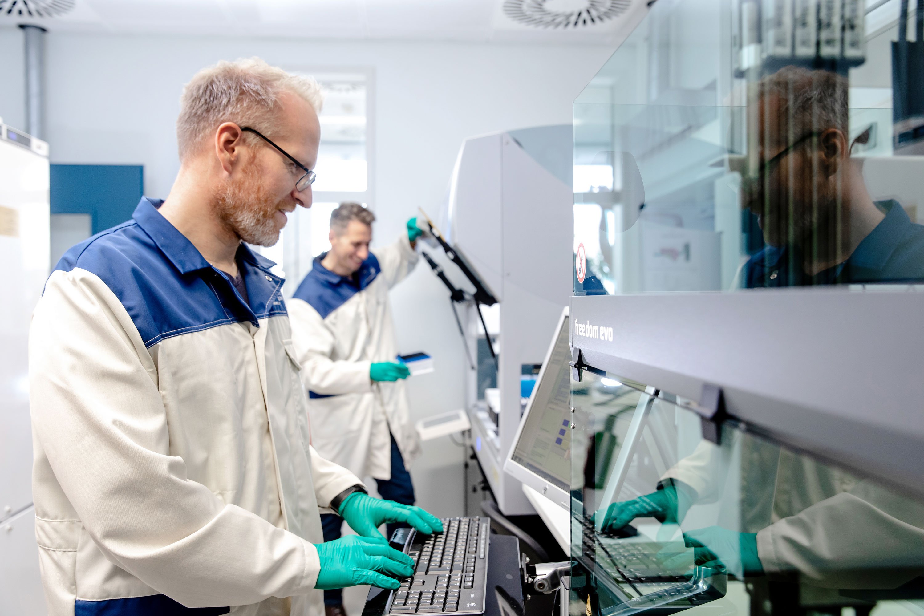 Two scientists operating large liquid handling machines