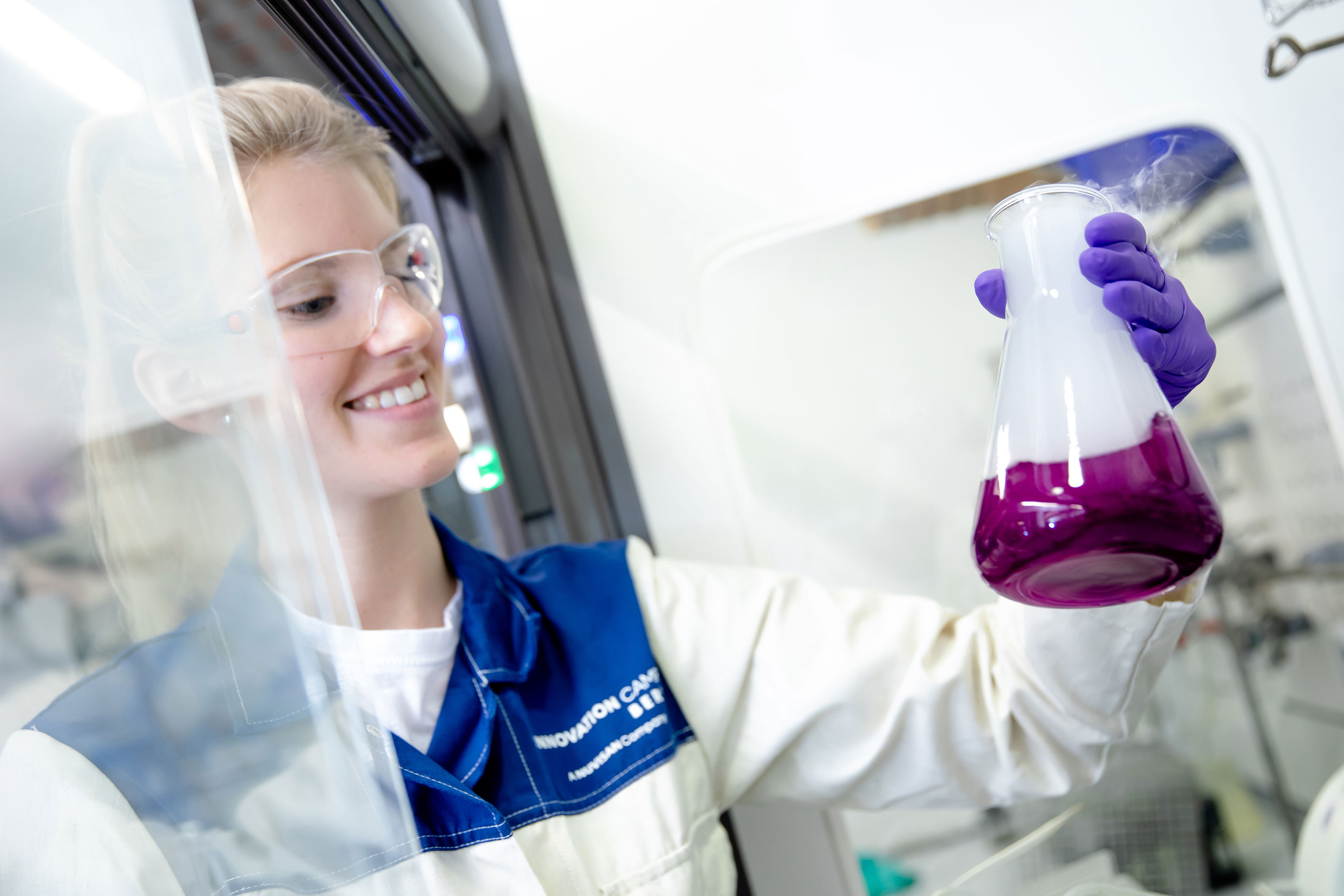Scientist in a lab coat inspecting a colored solution