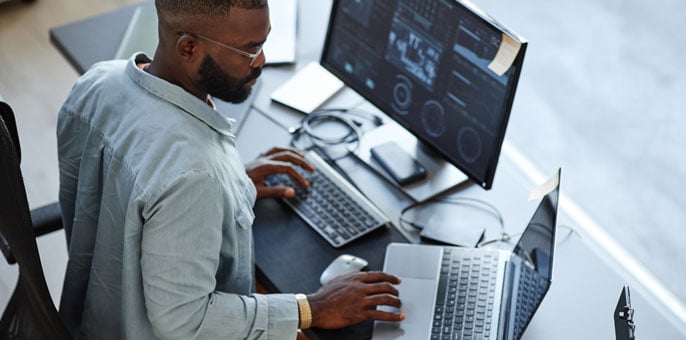 High-angle view of software developer working on computers and data systems in office