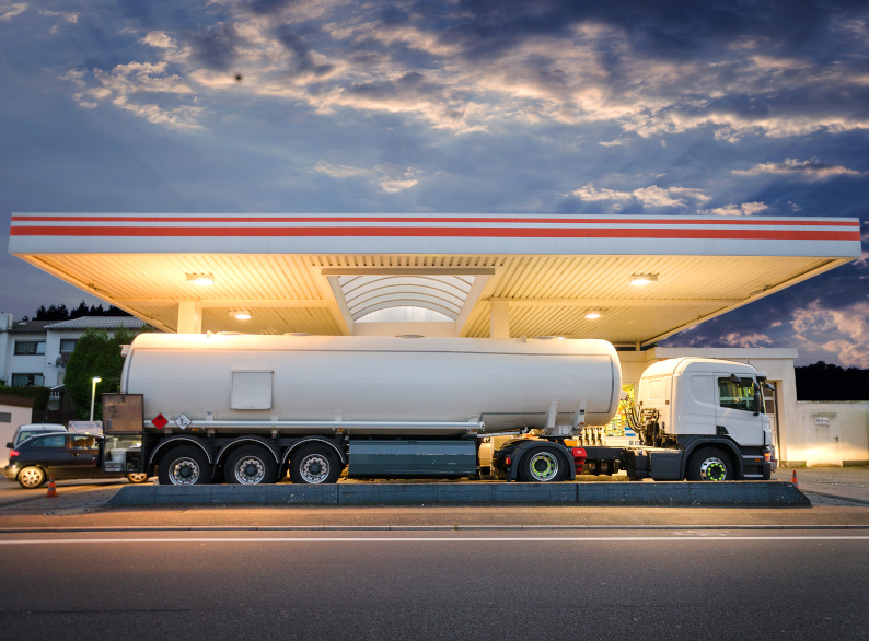 Fuel tanker truck delivering gasoline at a service station as part of a commercial fuel distribuition