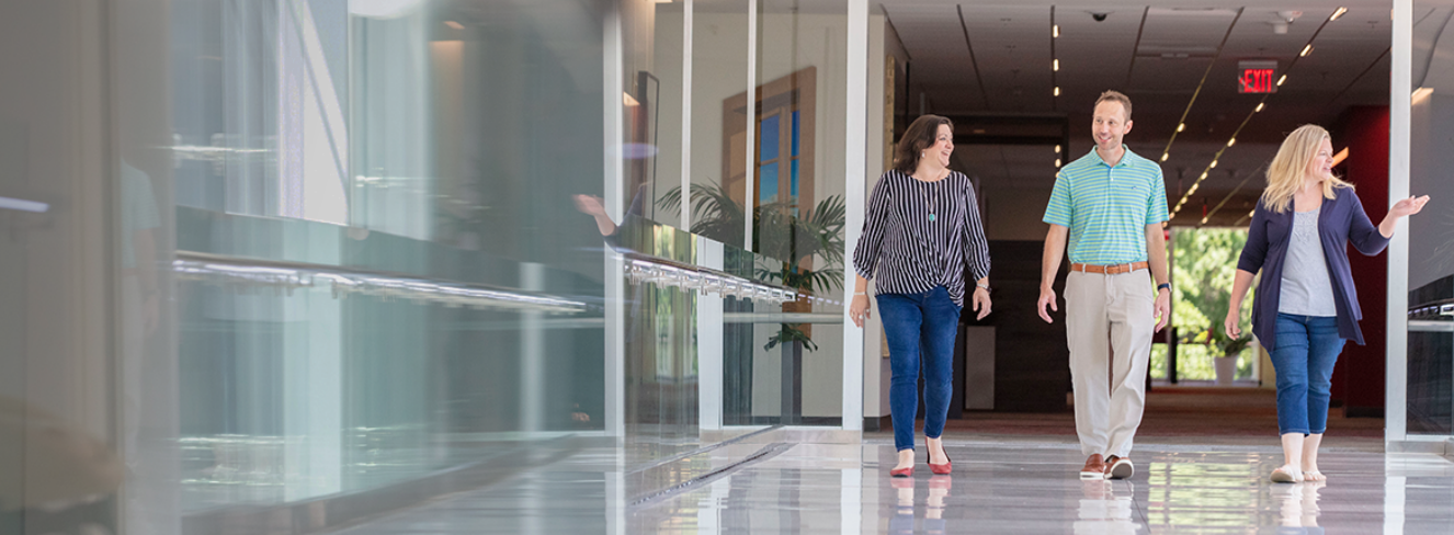 two women and one man walking down the hall in headquarters