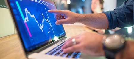 detail of hands inspecting stock performance chart on laptop
