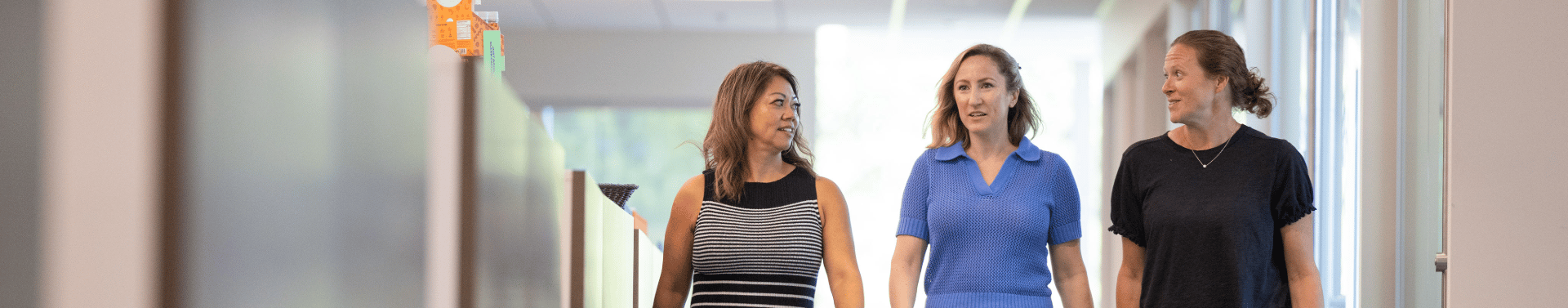 three women walking down a hall in our headerquarters building