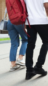 Students walk together on a school campus, carrying backpacks, books and other personal items.
