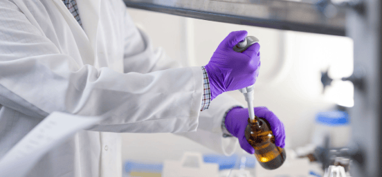 Laboratory technician wearing protective gloves uses a pipette to handle liquid samples for research