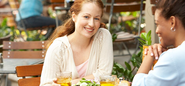 woman sitting at table in outdoor cafe smiling