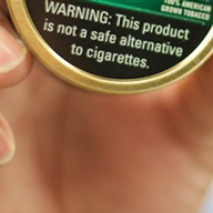hand holding a can of tobacco with warning label