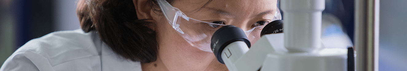 woman scientist looking into micoroscope in lab