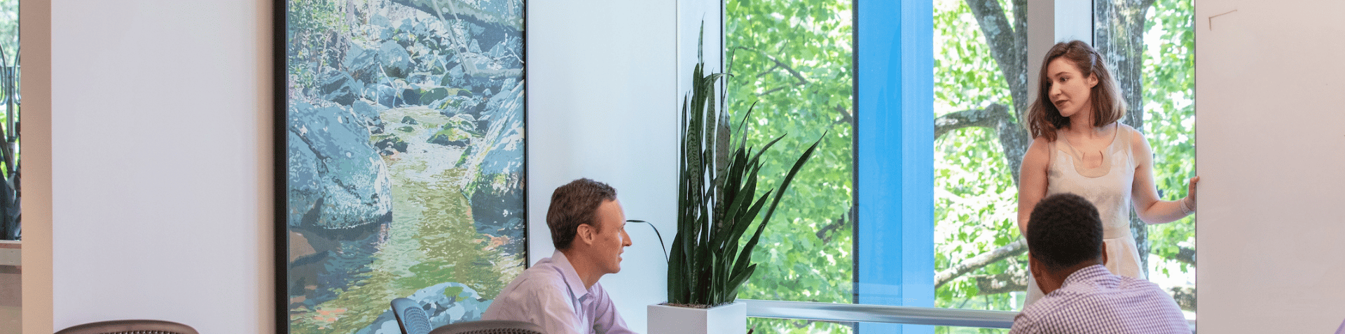 Two employees talk across a counter in a modern office space with open seating and collaborative areas