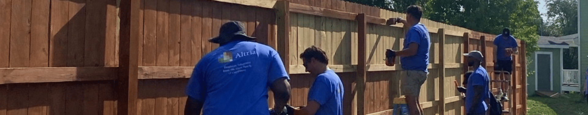 Altria employees volunteer together to paint and improve a community fence during a neighborhood service project.