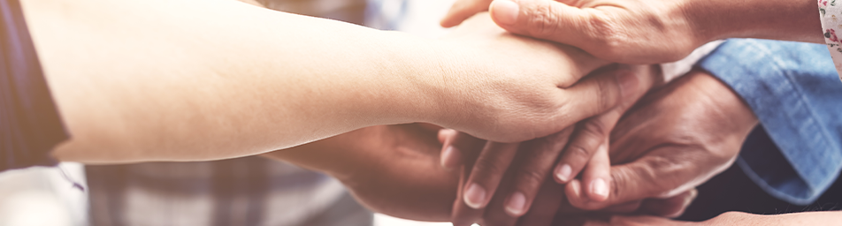 Many hands of different races and ages touching