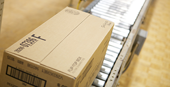 Product packaging - Closed brown box carton on a silver conveyor belt