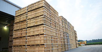 stacked packaging crates  - Wooden packing crates stacked roof high out front of the open doors of a storage building
