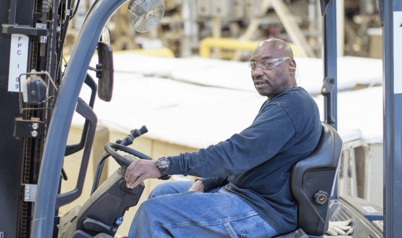 man sitting on fork lift in manufacturing facility