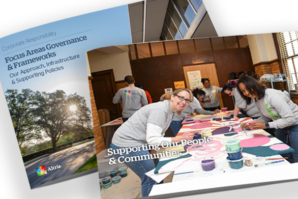 Supporting our People & Communities section of the Focus Areas Governance & Frameworks report featuring employees in grey long-sleeved polos at a volunteering event, leaning over a table painting and an open copy of the report below