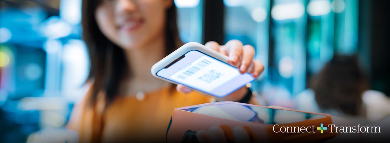 Female with shoulder-length dark hair in orange top holding a cellphone showing a scan-code over a dark orange code reader. The Connect + Transform logo is on the bottom right and the background is muted.