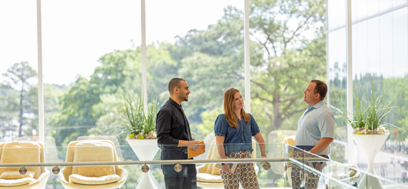 two men and a women talking in an open office area
