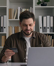 Smiling satisfied male client Caucasian man businessman worker at home office use laptop pay money online with bank credit card internet easy financial app business shopping e-commerce order web store