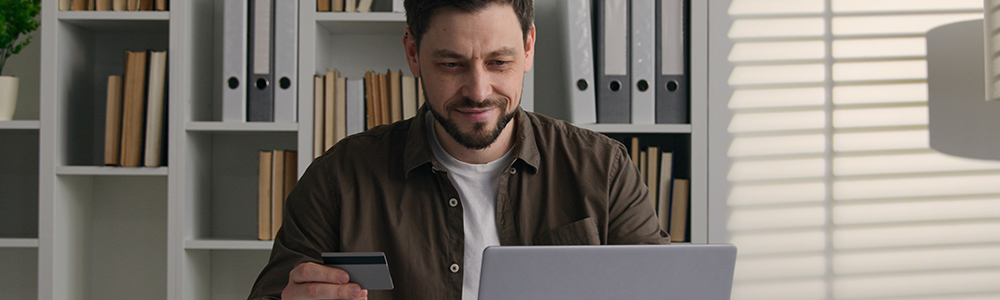 Smiling satisfied male client Caucasian man businessman worker at home office use laptop pay money online with bank credit card internet easy financial app business shopping e-commerce order web store