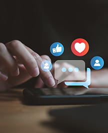 Shadowed imaged of a woman's hand using a smart phone.  writing on the screen of a mobile phone with concepts in white of social media and digital online in blue and red colored bubbles