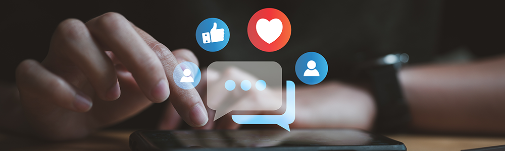 Shadowed imaged of a woman's hand using a smart phone.  writing on the screen of a mobile phone with concepts in white of social media and digital online in blue and red colored bubbles