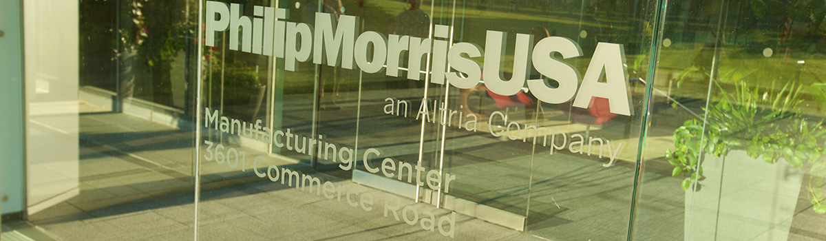 Close up of the entry glass doors of the Philip Morris USA manufacturing center with the company logo frosted in white across the doors