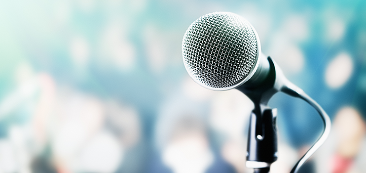 Silver microphone on a black stand with an out of focus blue background