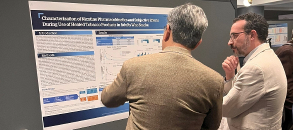 Two men standing in front of a scientific poster looking intently at it