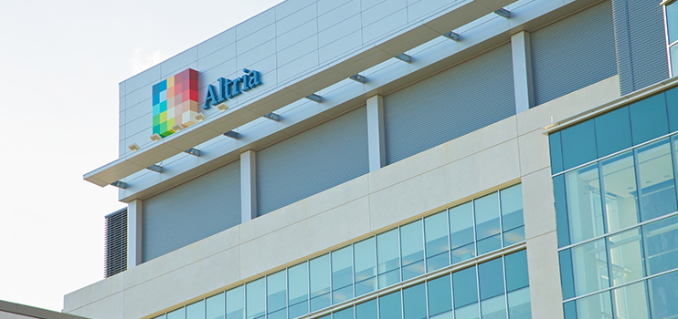 Close-up of the top white external side wall of a building showing the windows of two levels with the Altria logo at the top of the building.