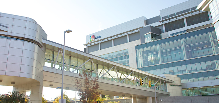 Outside of a building showing a walkway with windows its entire length, from the parking lot to the 2nd level and street lamps outside.