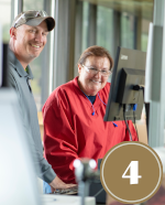man and women smiling while looking at computer screen