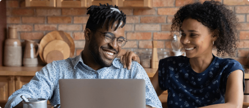 Smiling couple looking at laptop together.