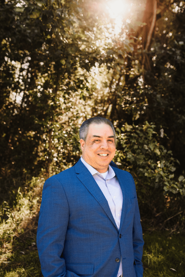 a man smiling in front of a tree