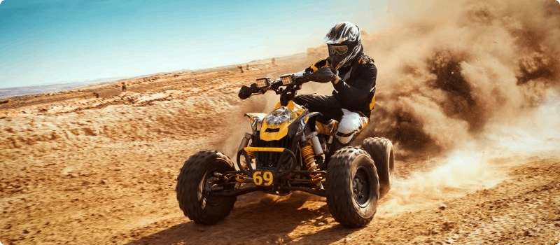 A person riding an ATV on a dirt hill. 