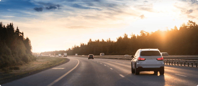 Cars driving on an open road in the early evening.