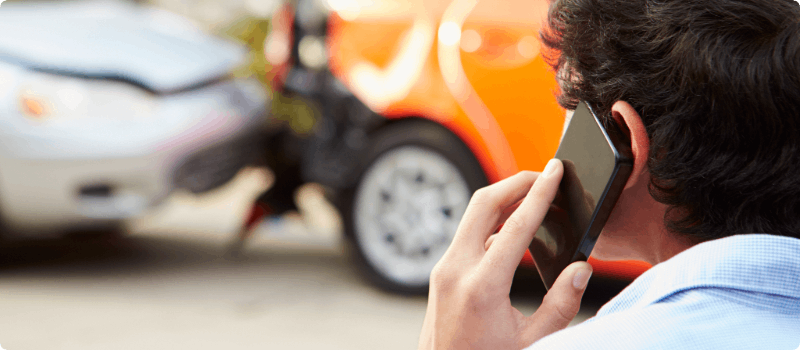 Person on the phone looking at two cars pulled over on the side of the road after an accident.