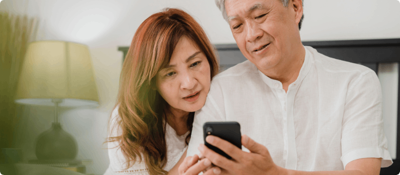 Couple sitting together while looking at their phone.